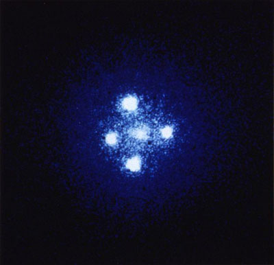 Figure 9 : Croix d'Einstein (QSO 2237+0305). L’observation de ce quasar situé à 8 milliards d’années-lumière se fait par déflexion à travers une galaxie-lentille située 20 fois moins loin, à 400 millions d’années-lumière (Photographie ESA, prise par le télescope américain Hubble).